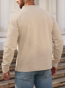 Macro detail of the men's beige jacquard knit sweater showing texture and stitching