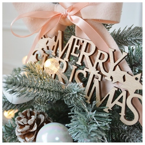 Close-up of Merry Christmas wooden sign with pine cones, needles and warm fairy lights