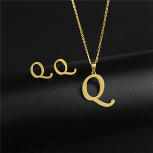 Detail of gold letter Q pendant necklace and matching stud earrings on black background