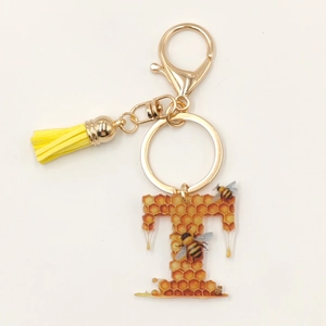 Detail of letter T acrylic honeycomb keychain with yellow tassel and golden clasp
