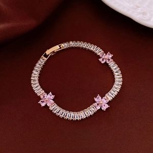 Zircon heart flower bracelet with gold base and pink gems on a burgundy background