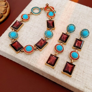 Vintage jewelry set with turquoise, ruby stones, and tassels on a linen display