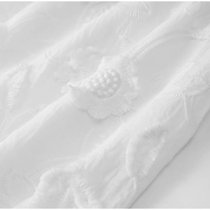 Gros plan sur le tissu blanc d'une robe avec broderie florale et détails texturés
