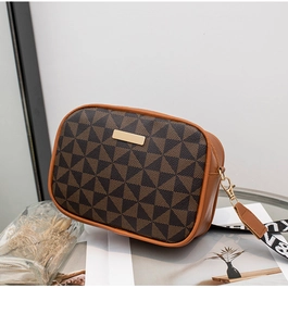 Detail of a brown geometric crossbody bag with a gold zipper and wide lettered strap