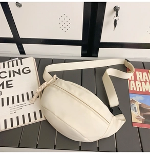 Detail of off-white canvas crossbody bag with woven zipper pull and adjustable strap