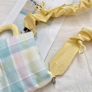 Detailed close-up of a pastel plaid water bottle bag with yellow ruffled shoulder strap