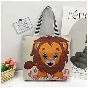 Detail of embroidered lion tote bag with striped straps in a cozy lifestyle setting