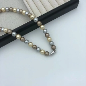 Detailed close-up of mixed color pearls in white, gold, and brown with a silver clasp