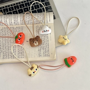 Macro shot of 5-piece plush animal hair ties with cute embroidery on a laptop and book