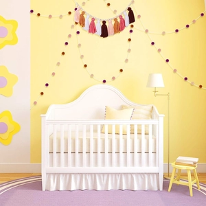 Nordic wall hanging with colorful tassels and wooden beads in a cozy baby room decor
