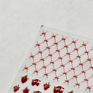Detail shot of strawberry and pink bow pattern nail stickers on white leather