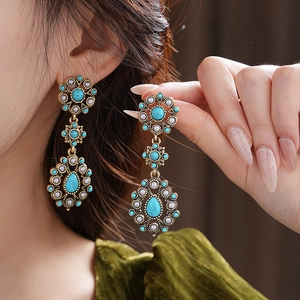 Detailed shot of bronze vintage earrings with turquoise, pearls and teardrop pendants