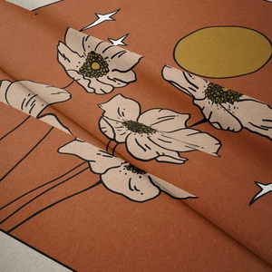 Close-up of bohemian wall tapestry with golden sun and floral patterns on terracotta fabric