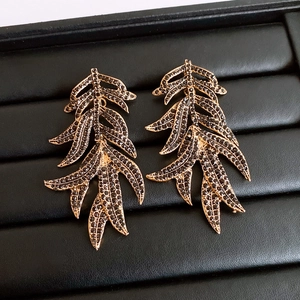 Detail of vintage gold leaf earrings with black rhinestones on a textured black tray