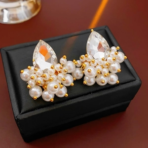 Macro detail of drop-shaped crystals and cluster pearls on a black leather jewelry box