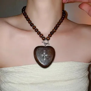 Collier ethnique en perles de bois avec pendentif cœur et croix en argent
