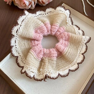 Close-up of knit lace scrunchie in beige and coffee brown colors on a wooden tray