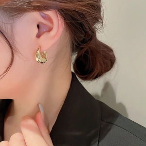 Boucles d'oreilles géométriques dorées en forme de U portées par un mannequin