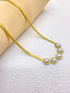 Close-up of golden snake chain necklace featuring five elegant white pearls in detail