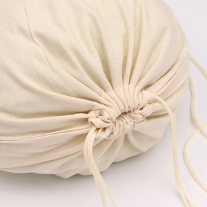 Close-up of a beige cotton linen drawstring bag with textured fabric and white cords