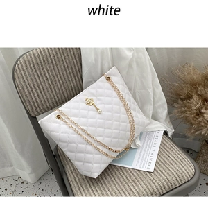 Close-up of quilted white tote bag with gold chain strap and crown pearl pendant