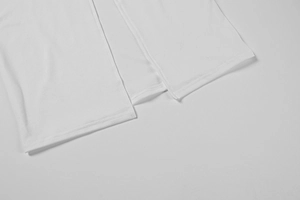 Vue macro de l'ourlet de robe blanche tricotée avec surpiqûre double et fente latérale
