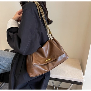Close-up of brown PU leather tote with gold hardware and woven chain strap details