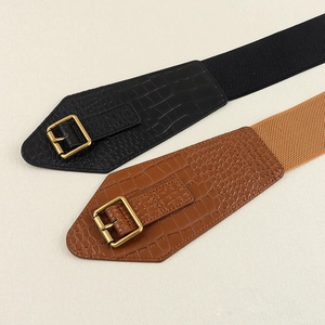 Detail of crocodile embossed wide elastic belts with golden square buckles in black and brown