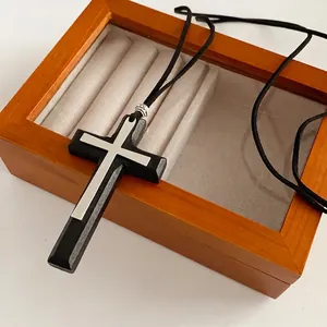 Minimalist double cross pendant necklace featuring black wood and silver metal on a jewelry box
