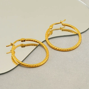 Chic textured gold hoop earrings in stainless steel displayed on a reflective mirror