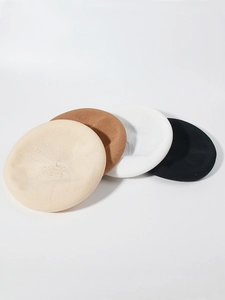 Close-up of knitted beret hats in beige, brown, white, and black colors on white background