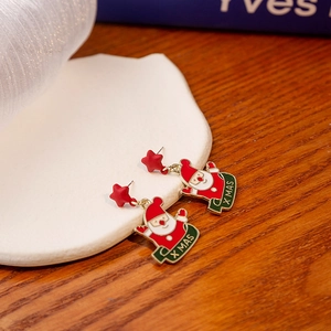 Detailed view of Santa Claus earrings on a white tray with festive X MAS text design