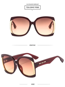 Detail of square oversized sunglasses with burgundy frame and golden arrow accents