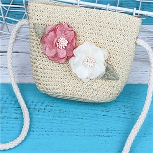 Détail d'un sac bandoulière en paille avec fleurs en tissu et bandoulière en corde