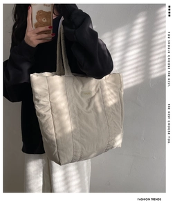 Detail of soft cream quilted nylon tote bag with natural window light and shadow textures