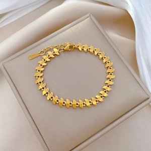 Bracelet en acier titane doré avec maillons plumes sur écrin beige et tissu satiné