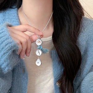 Détail d'un pendentif bonhomme de neige avec ruban bleu sur une chaîne en argent fin