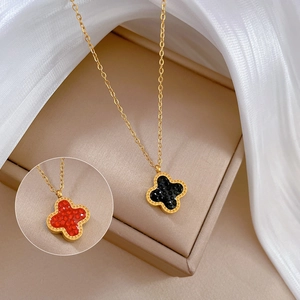 Macro shot of double-sided four-leaf clover pendant necklace with black and red inlay detail