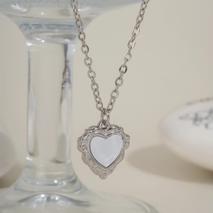 Vue macro d'un pendentif cœur en nacre avec dentelle rétro et chaîne argentée polie