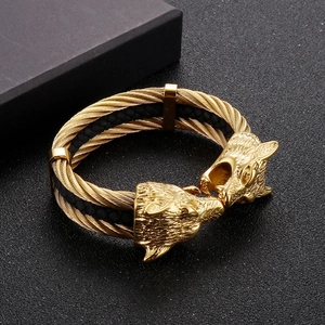 Detailed close-up of golden braided cable steel bracelet featuring dual wolf head ends