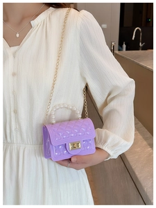 Detail of purple jelly bag with quilted texture, pearl handle, and golden chain strap