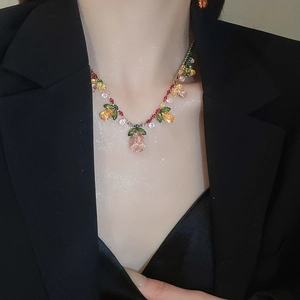 Close-up of pink teardrop crystal floral necklace on model with golden metal chain
