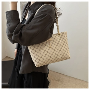 Side view of beige tote bag with geometric diamond patterns and metal chain strap