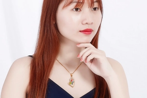 Detail of a gold heart pendant necklace featuring a colorful floral clover inlay