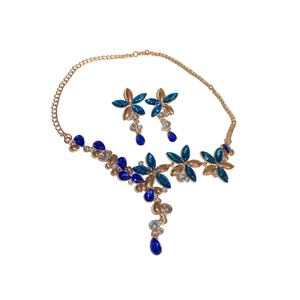 Vintage jewelry set with gold floral teardrop necklace and blue crystal earrings on white