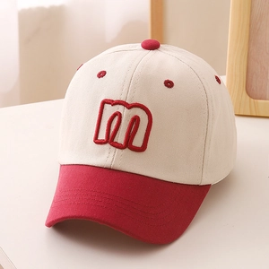 Close-up of red and white cotton baseball cap with embroidered letter m and visor detail