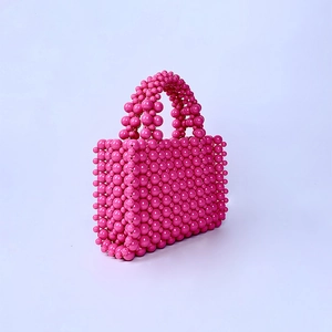 Close-up of pink handmade beaded handbag with high-gloss acrylic pearls and woven texture