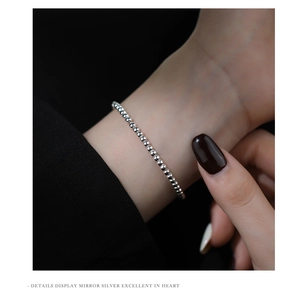 Detail showing the adjustable silver beaded chain bracelet on a model wrist in macro view
