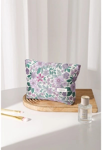 Close-up of floral embroidery detail and branded fabric label on a vintage vanity bag