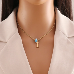 Close-up of golden letter I pendant with blue evil eye bead on a twisted chain